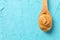 Spoon with peanut butter on color background, space for text