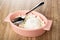 Spoon in pink bowl with grained cottage cheese and sour cream on table