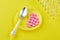 Spoon and pink tablets on saucer, ampoules on yellow background