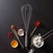 Spoon with red pepper, metal whisk, vintage knife raw egg and flour on a black concrete background with copy space