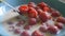 Spoon scoops fresh raspberries with milk from a blue plate close-up