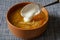 A spoon with sour cream and cabbage soup in a brown earthenware bowl on a blue tablecloth