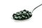 Spoon with spirulina tablets on white background
