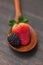 Spoon with strawberry and blackberry on a wooden surface