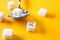 Spoon and sugar cubes with funny faces on color background. Diabetes concept