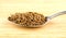 Spoonful of cumin seeds against wooden background