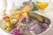 Spoonful of mustard sauce pours over slices of pickled herring with chopped red onions and herbs.