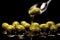 A spoonful of olive oil being drizzled over a pile of green olives on a black background