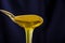 A spoonful of sweet, fresh honey. Honey in a spoon on a dark blue background. Close-up. Mod flowing down from a spoon.