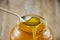 A spoonful of sweet, fresh honey. Honey in a spoon on a jar background. Close-up. Honey flows from a spoon into a jar.