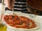 Spooning Tomato sauce onto a Pizza Base