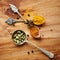 Spoons, spice and selection of color for seasoning on kitchen table, turmeric and cardamom for meal. Top view