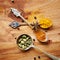 Spoons, spice and selection of cuisine for seasoning on kitchen table, turmeric and cardamom for meal. Top view