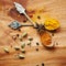 Spoons, spice and selection of seasoning for diet on kitchen table, turmeric and cardamom for meal. Top view, condiments