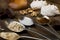 Spoons with sugar, coffee, oats and meringue, chocolate marshmallow, honey and nuts on a real brown wooden table.