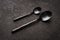 Spoons, teaspoons and regular ones, a couple. They're lying on a dark table. design for a restaurant or coffee shop