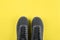 Sport background. Grey sneakers on yellow background. Top view, flat lay. Concept of color of year