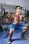 Sport, bodybuilding, lifestyle and people concept - young man with barbell doing squats in gym