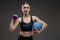 Sport caucasian girl with slim figure do exercises with blue ball and purple dumddell  on black background