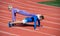 Sport fitness man and woman training together stand in plank and do push up on outdoor stadium racetrack wearing