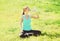 Sport, fitness, yoga concept - woman sitting on grass and drinking water from bottle in summer day