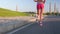 Sport footage, detail legs of woman running on empty street beside cornfields, shot in prores. Slow motion