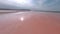 Sport fpv cinematic drone close speed flight above wonderful pink Salt lake with rocky bar under blue sky with light