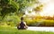 Sport girl meditating in nature green park at the sunrise