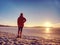 Sport girl in winter clothes running away to horizon of icy sea