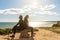 Sport girl and a woman on the shore of the Atlantic Ocean of Portugal, sitting on a stone and talking and thinking about