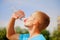 Sport, health and lifestyle concept. Portrait of young athletic man after training drinking water from bottle. Horizontal image