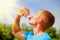 Sport, health and lifestyle concept. Young athletic man after training drinking water from bottle in sun rays