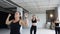 Sport and healthy lifestyle. Group of athletic girls in black bodysuits perform warm up step aerobic in fitness studio