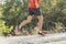 sport man with ripped athletic and muscular legs running downhill off road in jogging training workout