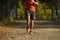 Sport man with ripped athletic and muscular legs running off road in jogging training workout at countryside in Autumn background