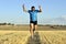 Sport man running outdoors on straw field doing victory sign in frontal perspective