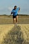 Sport man with sunglasses running outdoors on straw field ground in frontal perspective