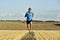 Sport man with sunglasses running outdoors on straw field ground in frontal perspective