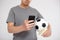 Sport, online bet, success, win and money concept - young man holding smart phone, euro money and  soccer ball over grey