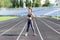 Sport in open air and health care concept. attractive fitness woman warm-up before run on the stadium track on sunny summer day