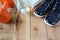 Sport shoes and towel, dumbbell, bottle of water on wooden.