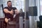 Sport stress motivation of heavy workout in fitness gym by bearded young male in black jersey sitting and pulling weight on