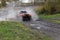 Sport SUV boosts water hurdle surrounded by splashes.