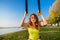 Sport woman doing  training outdoors with TRX at daytime. Total body resistance exercises for her healhty lifestyle