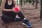 Sport woman injury at knee during jogging in forest. Pine woods background.  Medical and Healthcare concept. Nature and People