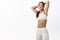 Sport and women health. Fit sportswoman in sportsbra and leggings, slim belly, holding hands behind head and smiling