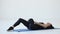 Sport, yoga, Pilates and fitness tutorials. The young brunette trainer is doing the laying-down gluteal stretches on the