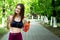 Sport young woman - smiling, with headpnones and water - outdoor in park