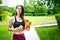 Sport young woman - smiling, with headpnones and water - outdoor in park