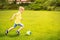 Sporting boy plays football in sunny park